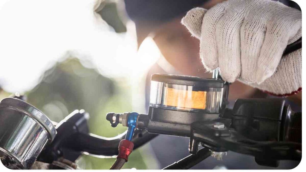 a person in gloves is fixing the fuel filter on a motorcycle
