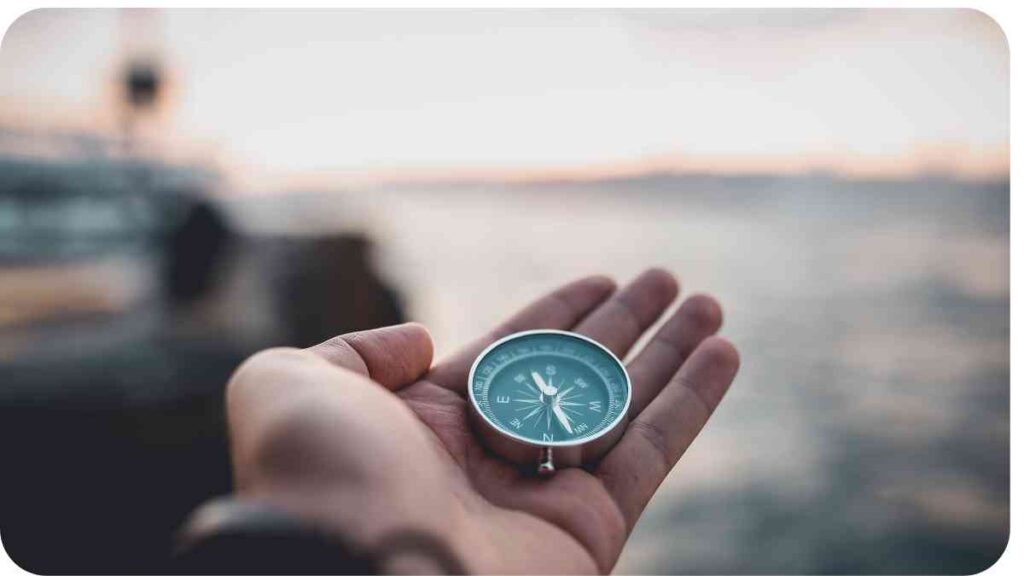 a person holding a compass in front of a body of water