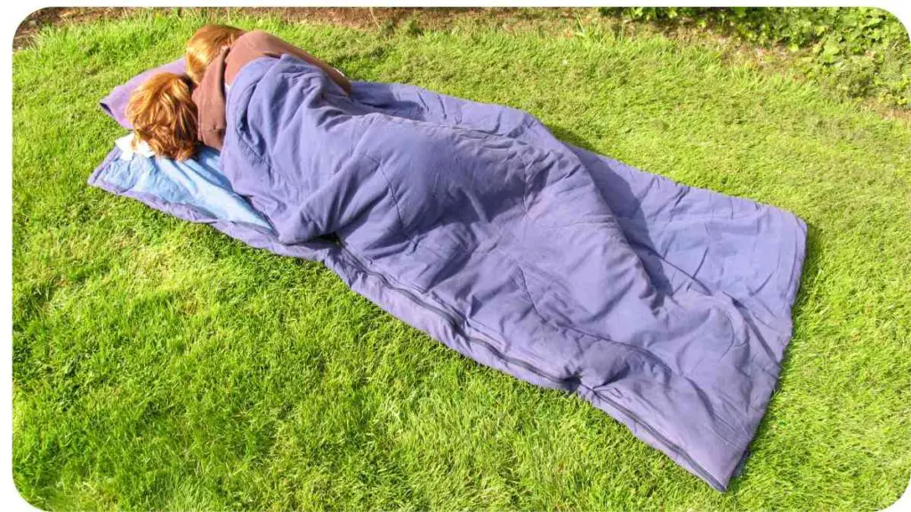 a person sleeping in a sleeping bag on the grass